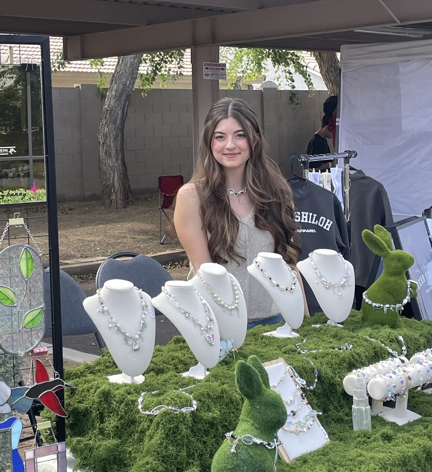 Nina at an outdoor market with the Bunny + Beads jewelry and stained glass display